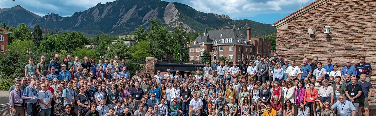 Large group of people in front of buildings and the flatiron mountains